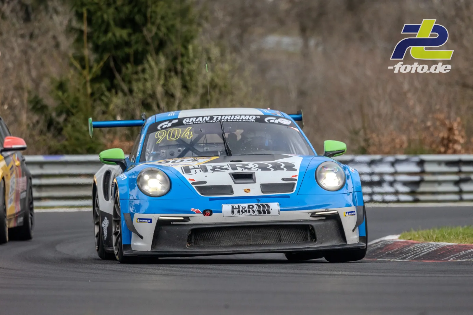 Porsche 911 GT3 Cup #904 in blau-weißer H&R-Lackierung während des NLS-Rennens auf der Nürburgring-Nordschleife, verfolgt von weiteren Fahrzeugen.