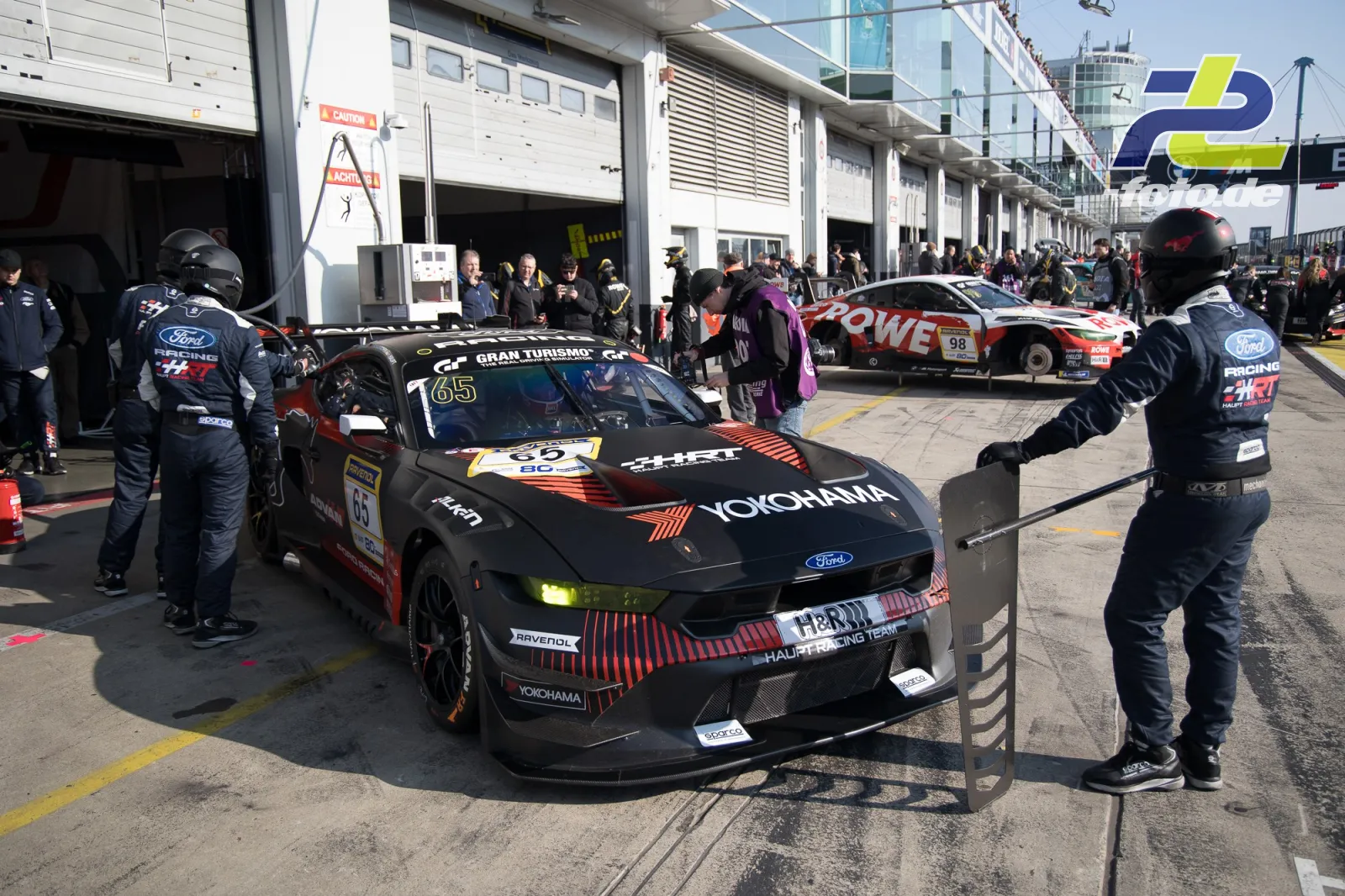 Ford Mustang GT3 wird in der Boxengasse des Nürburgrings von der Crew zu seinem Boxenplatz dirigiert.