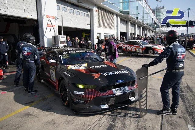 Ford Mustang GT3 wird in der Boxengasse des Nürburgrings von der Crew zu seinem Boxenplatz dirigiert.