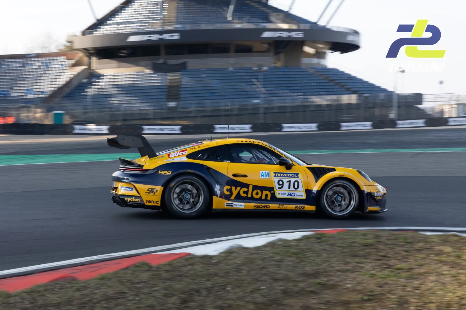 Gelb-schwarzer Porsche 911 GT3 Cup mit Startnummer 910 auf der Nordschleife vor dem Gebäude Mercedes-Arena beim Zeittraining.