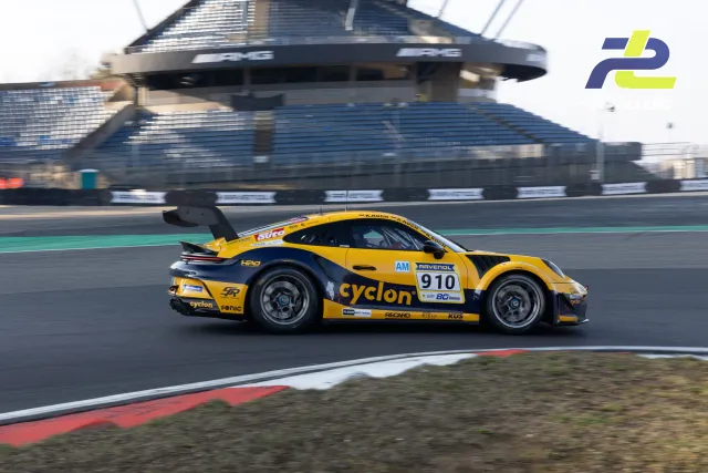 Gelb-schwarzer Porsche 911 GT3 Cup mit Startnummer 910 auf der Nordschleife vor dem Gebäude Mercedes-Arena beim Zeittraining.