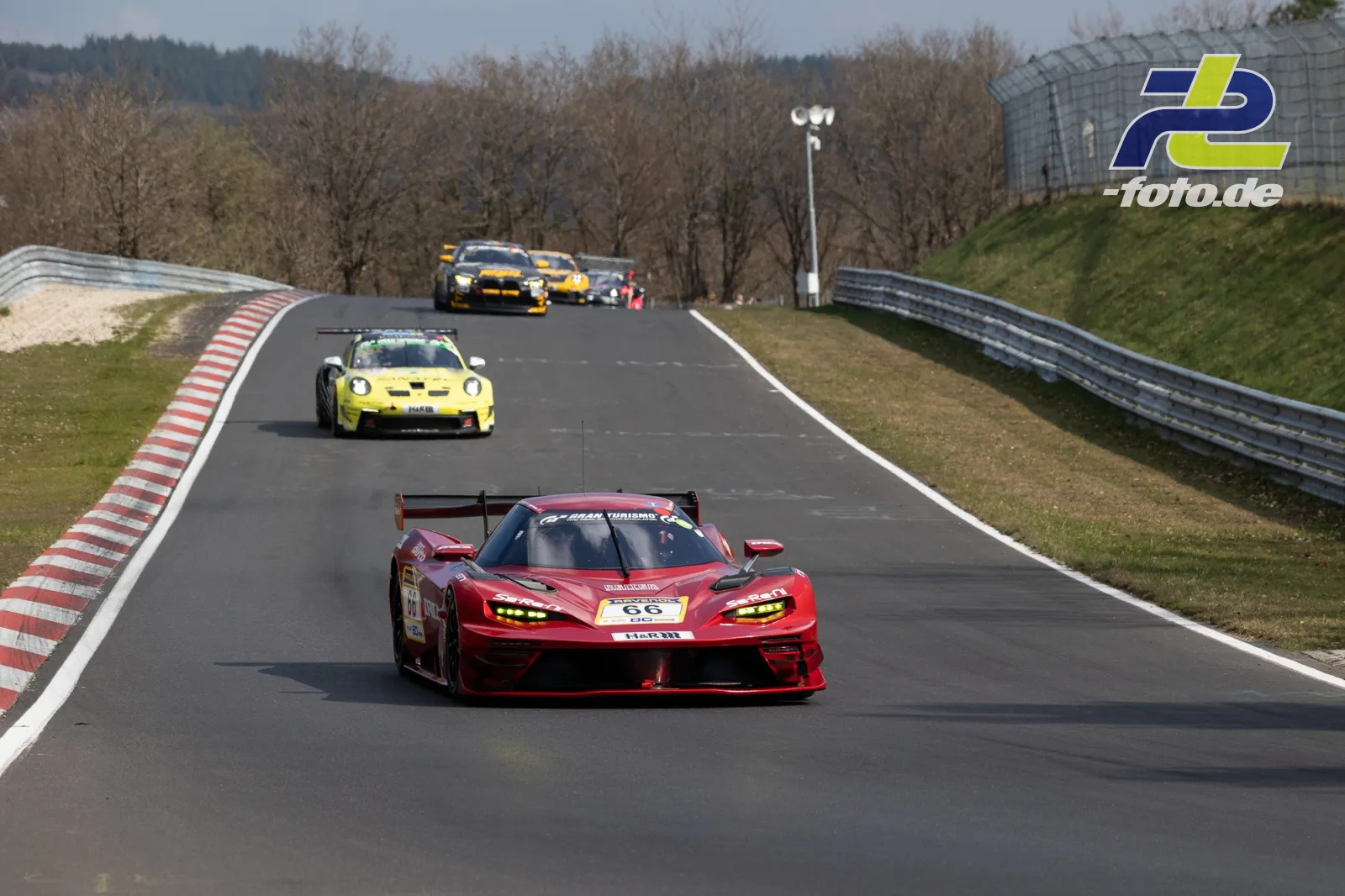 Drei Rennwagen auf der Nordschleife während des 58. ADAC Barbarossapreis, angeführt von einem roten Sportwagen mit Startnummer 66.