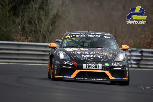 Porsche 718 Cayman GT4 Clubsport #941 in schwarz-oranger Lackierung während des NLS-Rennens auf der Nürburgring-Nordschleife.