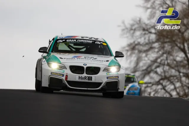 BMW im Gran Turismo-Design auf der Nürburgring-Nordschleife, gefolgt von einem zweiten Rennwagen im Hintergrund.