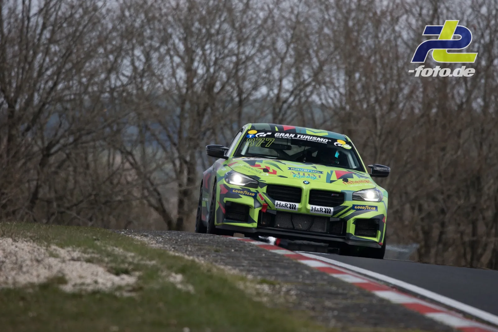 BMW M4 GT4 in grellgelber Lackierung mit roten und blauen Akzenten auf der Nordschleife während des NLS-Rennens.
