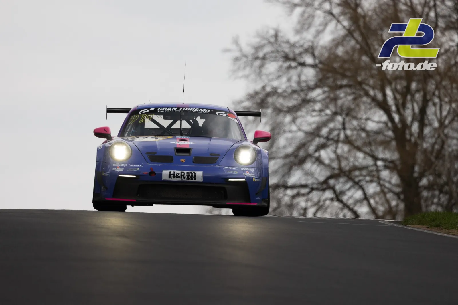Porsche 911 GT3 Cup frontal auf Bergkuppe der Nordschleife, Gran Turismo-Lackierung, bewölkter Himmel