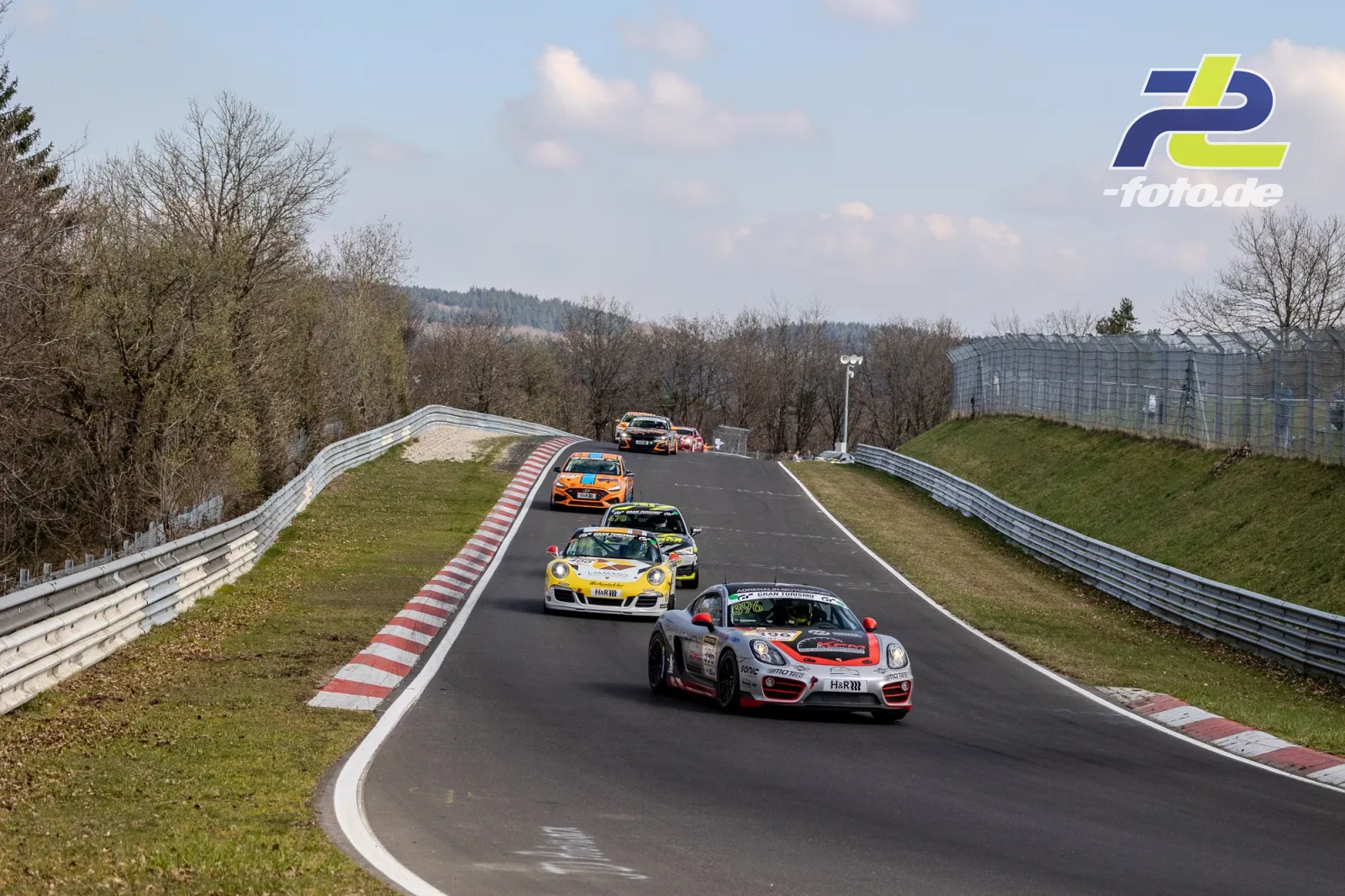 Mehrere Rennwagen fahren durch eine Bergauf-Kurve auf der Nürburgring-Nordschleife während des NLS-Rennens.