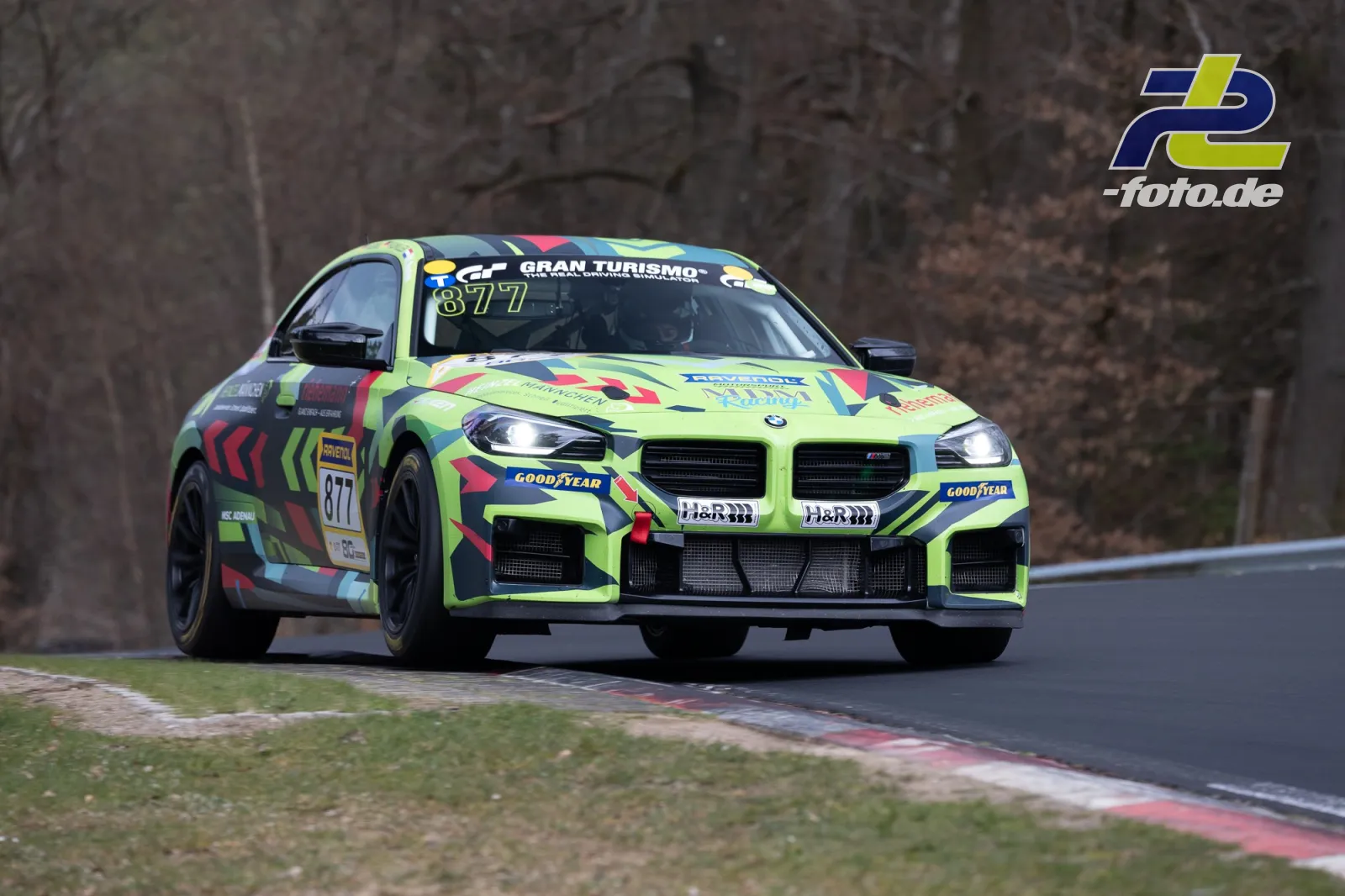 BMW M2 mit Startnummer 877 in auffälliger neongelb-bunter Lackierung während des Rennens auf der Nordschleife.