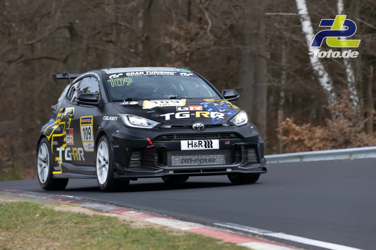 Toyota GR Yaris #109 in Kurve auf der Nürburgring Nordschleife beim NLS Rennen, schwarz-gelbe Lackierung mit weißen Felgen.