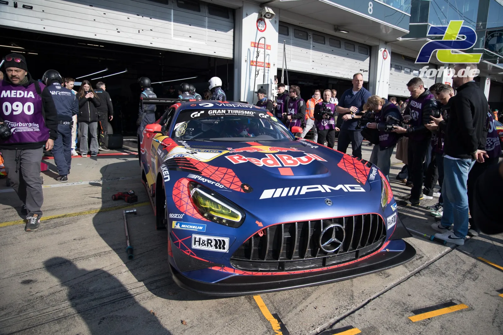 Mercedes-AMG GT3 mit Red Bull-Lackierung steht vor der Boxengasse, umgeben von Zuschauern und Medienpersonal