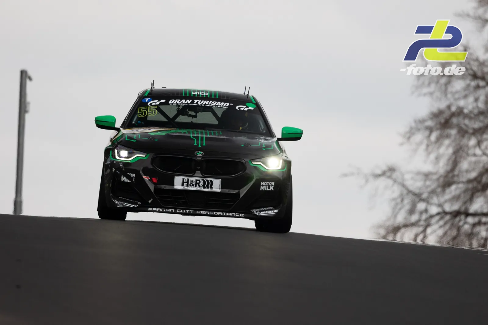 BMW über der Kuppe auf der Nordschleife beim NLS-Rennen, schwarze Lackierung mit grünen Akzenten und H&R-Kennzeichen