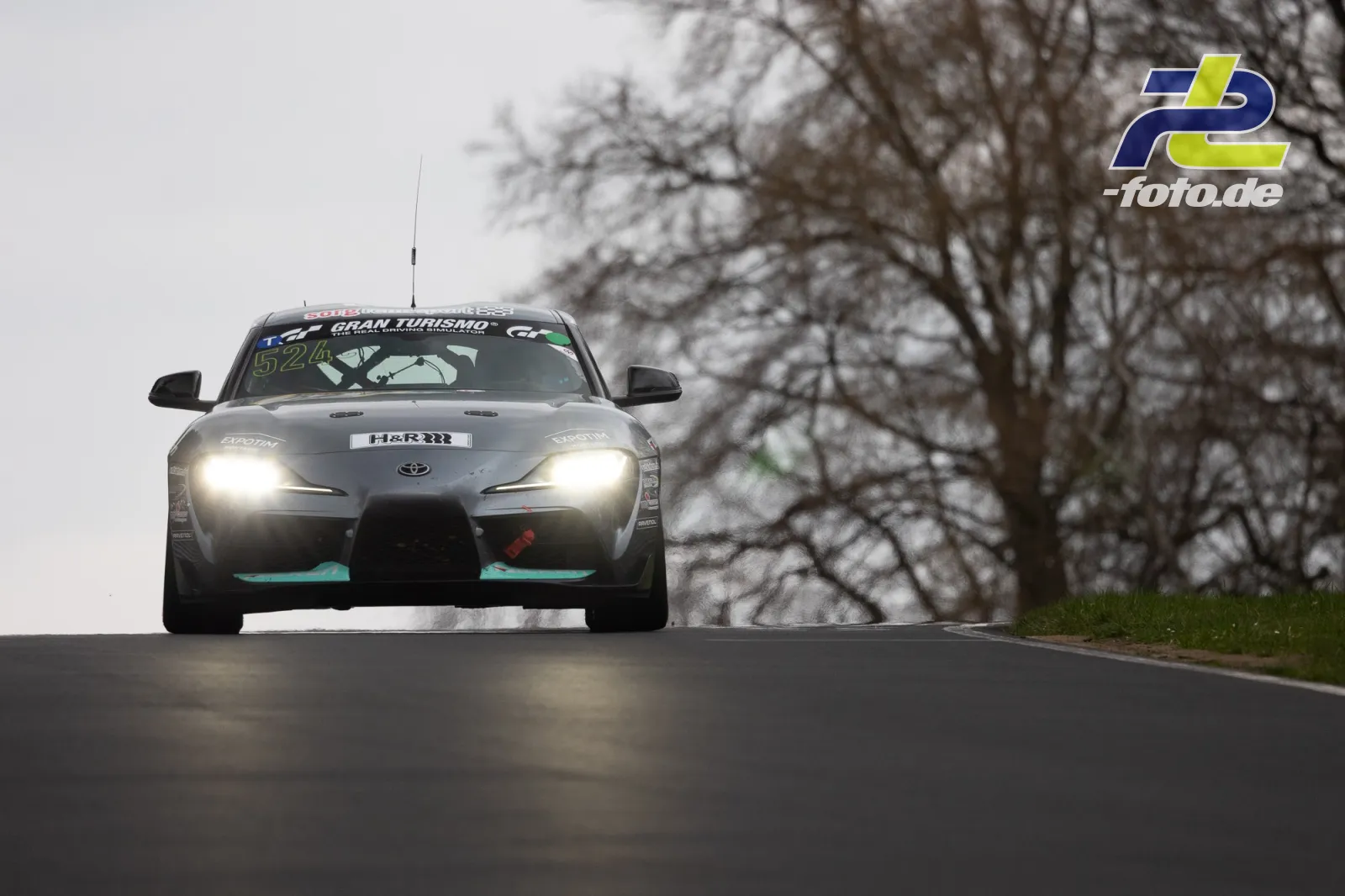 Toyota GR Supra GT4 (52) mit eingeschalteten Scheinwerfern frontal auf Kuppe bei trübem Wetter, Nordschleife.