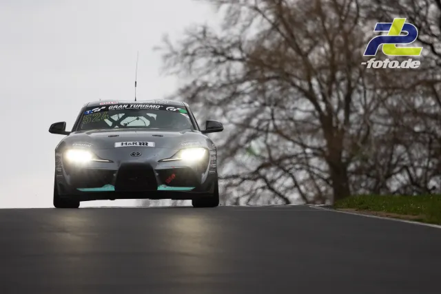 Toyota GR Supra GT4 (52) mit eingeschalteten Scheinwerfern frontal auf Kuppe bei trübem Wetter, Nordschleife.