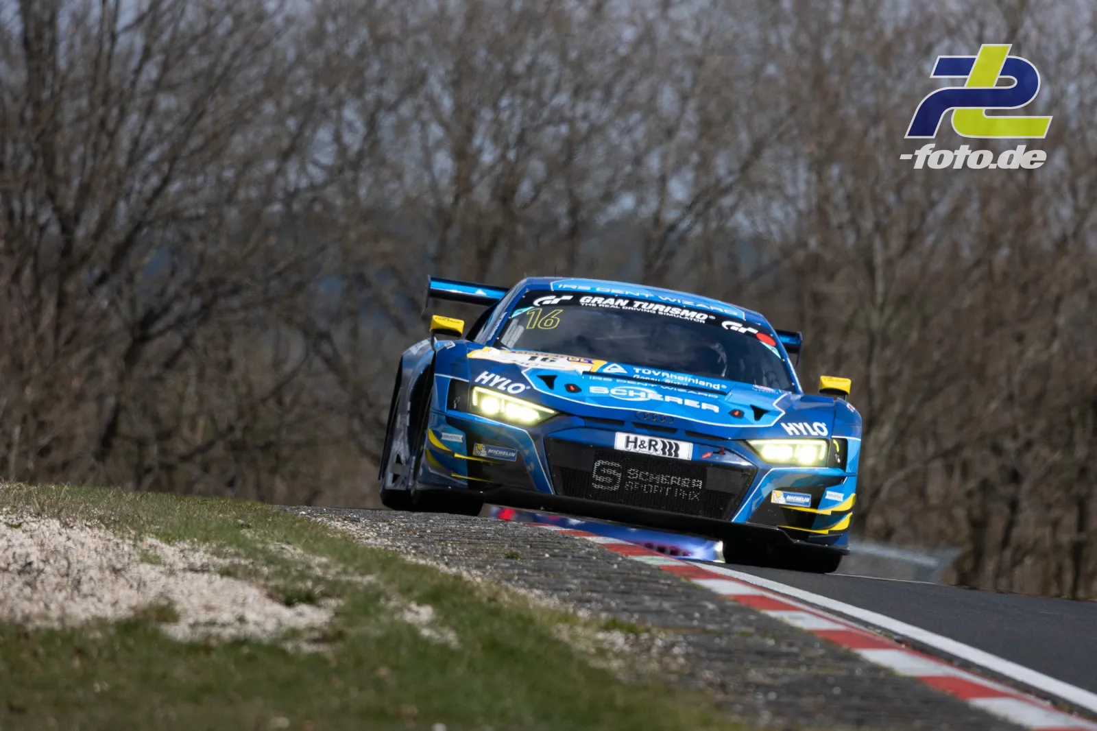 Blauer Audi R8 LMS GT3 mit Startnummer 16 in Kuppe auf der Nordschleife, im Hintergrund kahle Bäume
