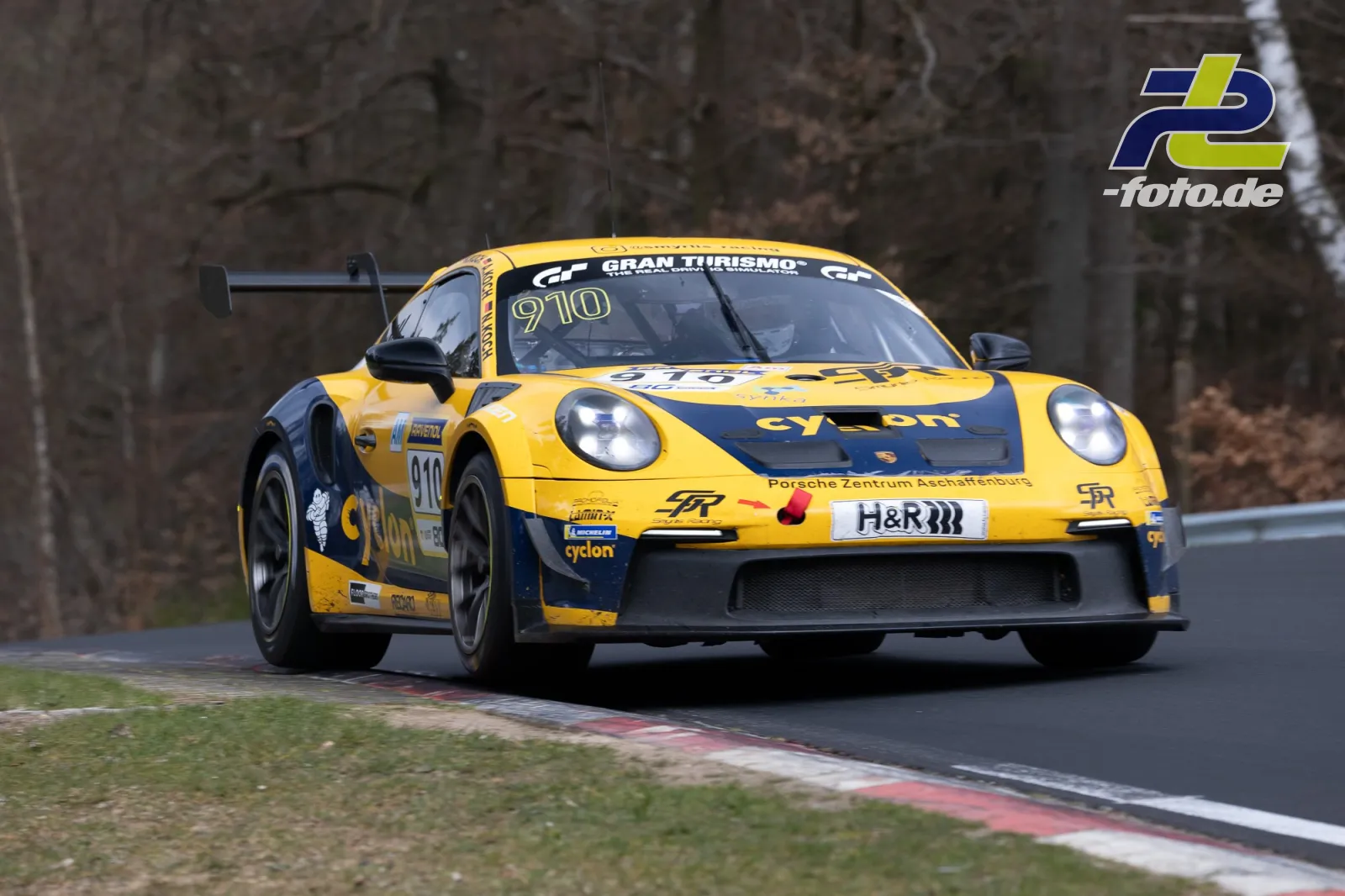 Gelber Porsche 911 GT3 Cup #910 in einer Kurve auf der Nürburgring-Nordschleife beim NLS-Rennen.