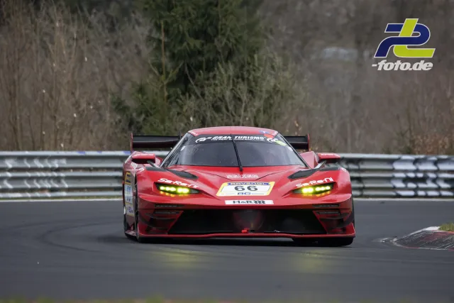 Roter Rennwagen mit Startnummer 66 auf der Nordschleife frontal in Fahrt, gelbe Scheinwerfer eingeschaltet.