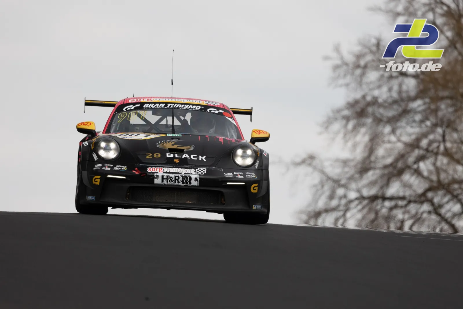 Porsche 911 GT3 Cup mit schwarzer Lackierung und gelben Spiegeln fliegt über die Kuppe am Nürburgring