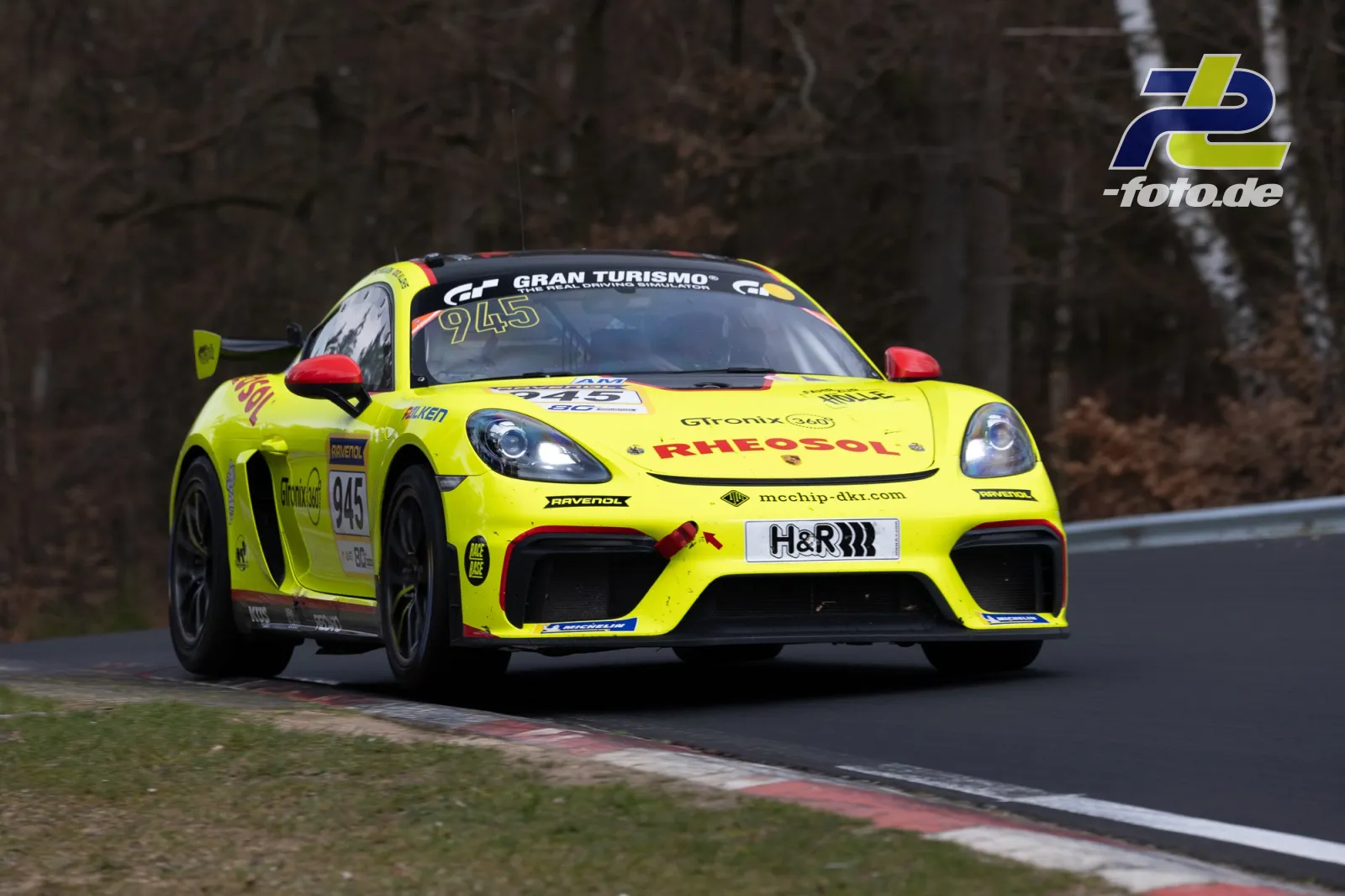 Gelber Porsche Cayman GT4 mit Startnummer 945 in Fahrt auf der Nordschleife bei der NLS.