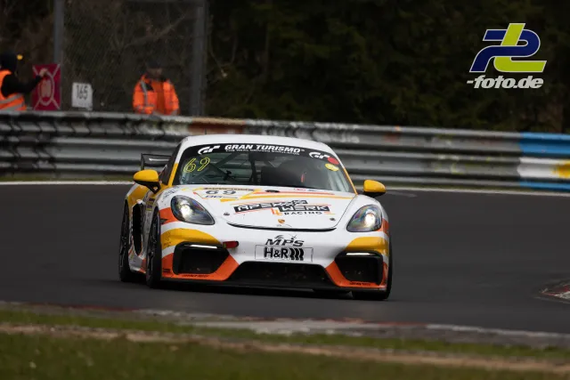 Porsche 718 Cayman GT4 Nummer 69 in weißer, gelber und oranger Lackierung auf der Nordschleife während des NLS-Rennens