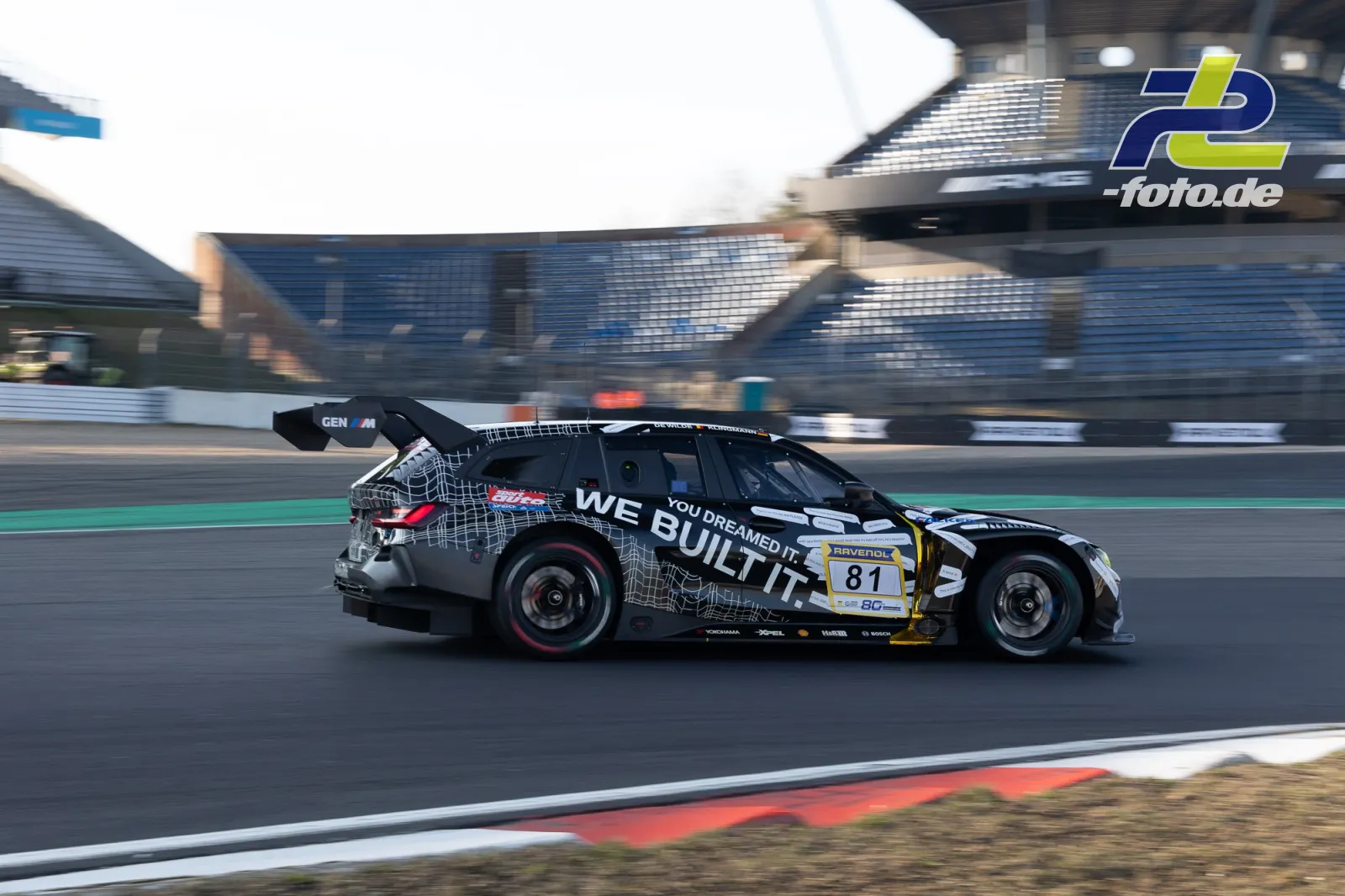 Rennwagen Nummer 81 mit schwarz-weißer Lackierung während des Zeittrainings auf dem Nürburgring, Tribüne im Hintergrund.
