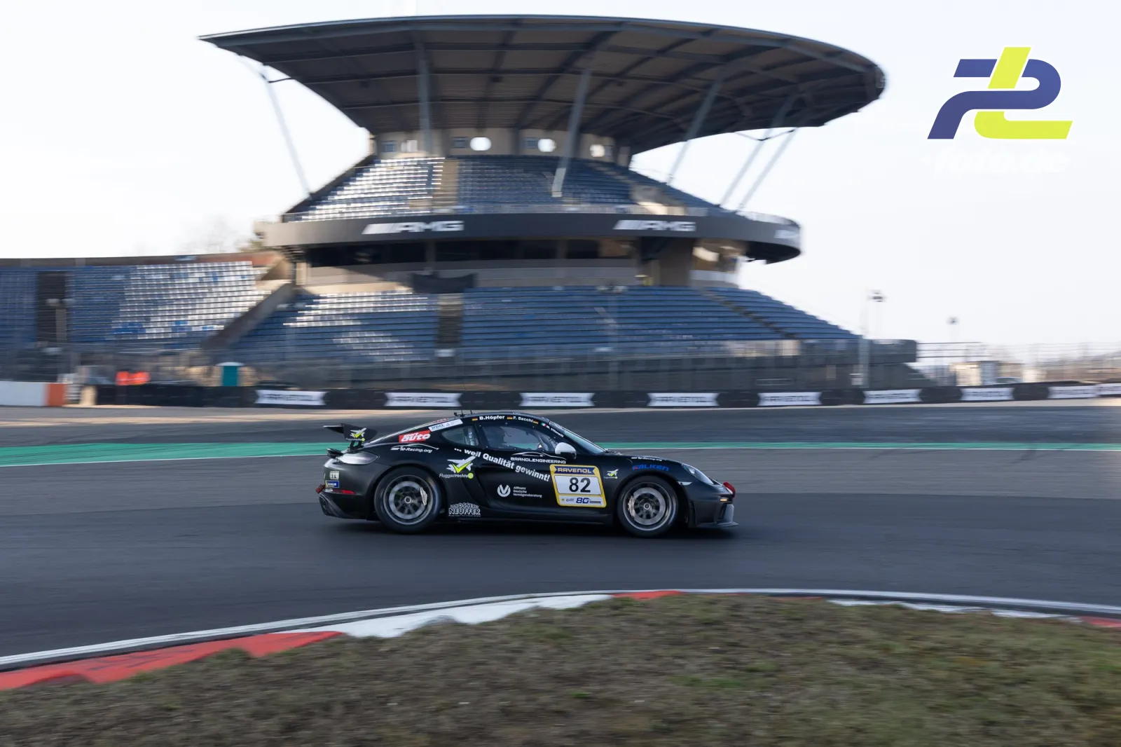 Porsche 911 GT3 Cup Nr. 82 in schwarzer Lackierung fährt vor der Haupttribüne am Nürburgring während des Zeittrainings.