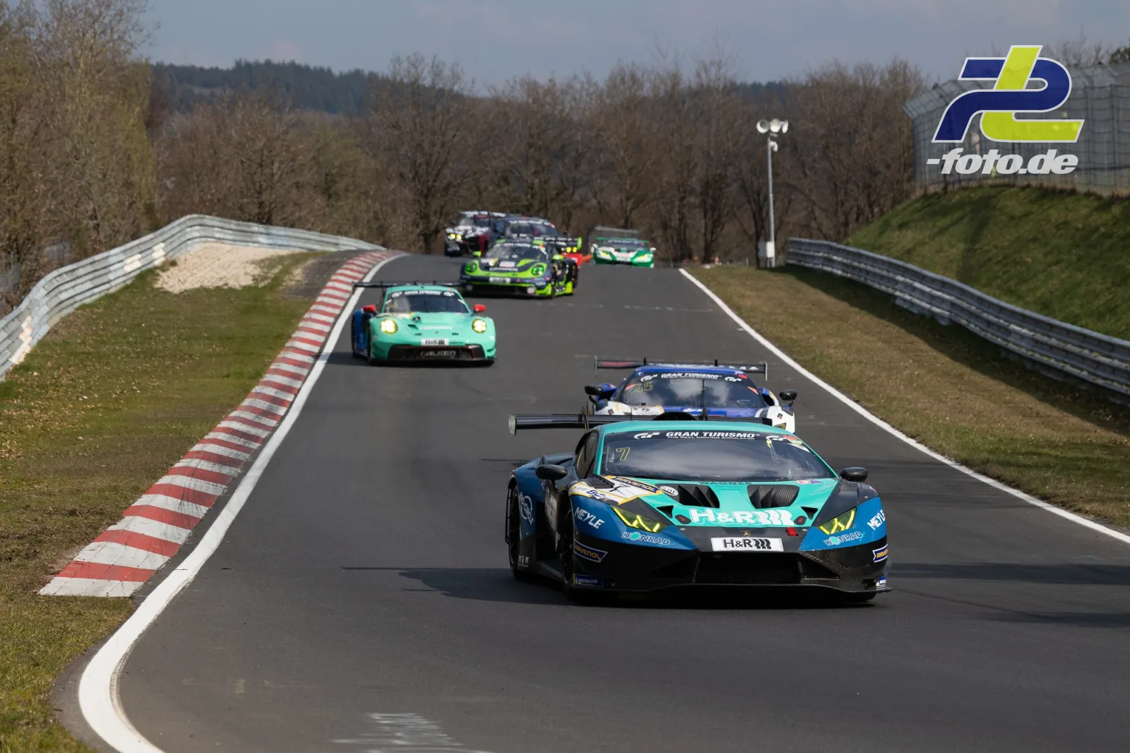 GT3-Fahrzeuge im Rennbetrieb auf der Nürburgring-Nordschleife, angeführt von einem türkis-blauen Lamborghini Huracán GT3 mit Startnummer 7.