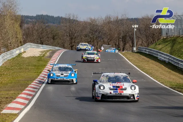 GT3-Fahrzeuge im Rennverkehr auf der Nordschleife, Porsche führt vor blauem Verfolger und weiteren Konkurrenten.