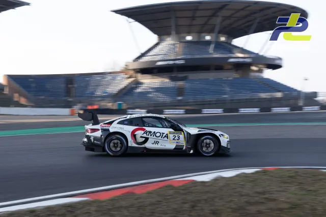 BMW M4 GT3 Nr. 23 in weiß-schwarzer GMOTA-Lackierung im Zeittraining auf der Nürburgring GP-Strecke vor der Haupttribüne.