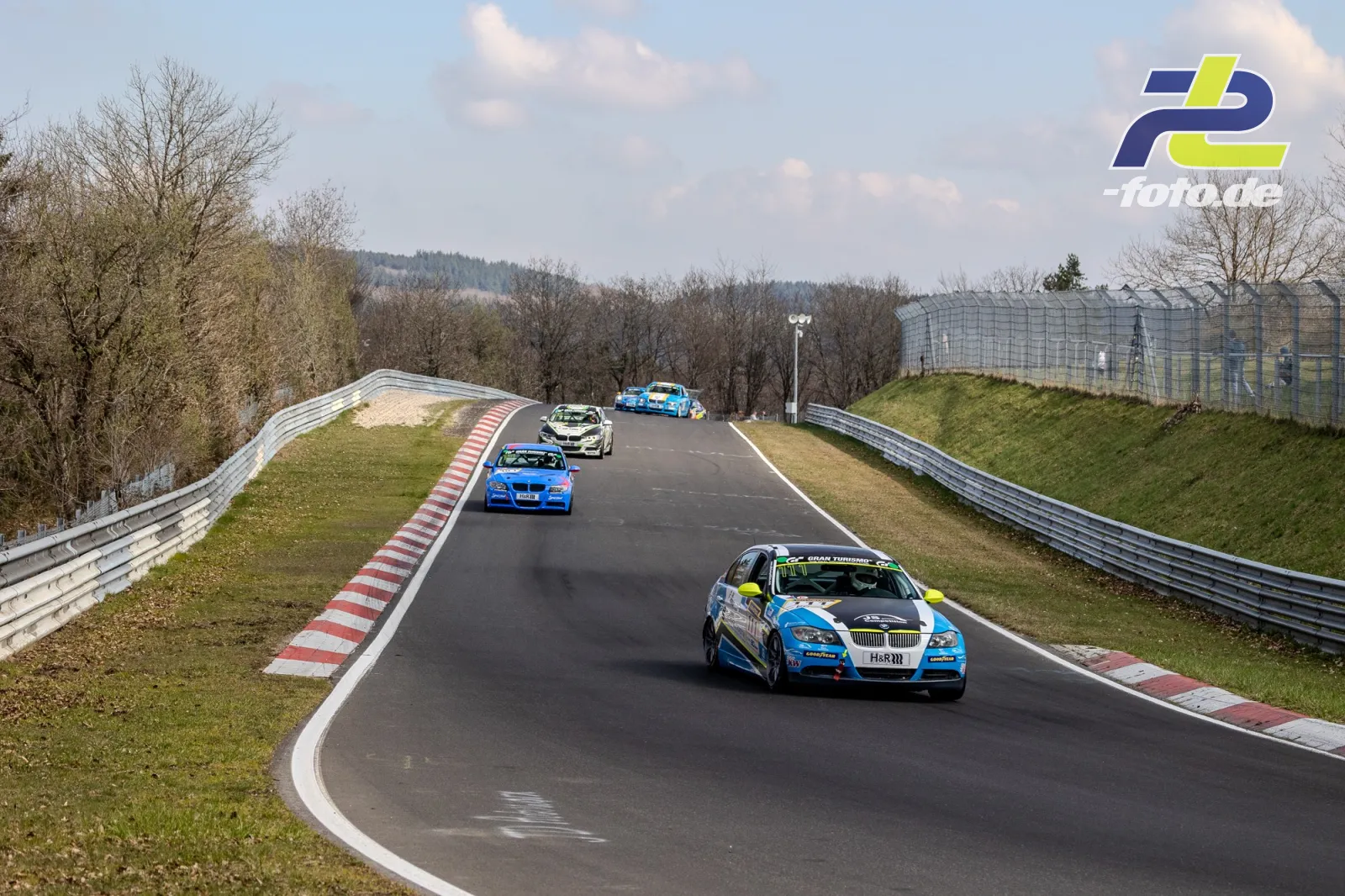 Vier Rennwagen in einer Kuppe auf der Nordschleife beim NLS-Rennen, angeführt von einem blauen BMW.
