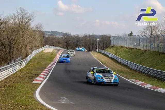 Vier Rennwagen in einer Kuppe auf der Nordschleife beim NLS-Rennen, angeführt von einem blauen BMW.