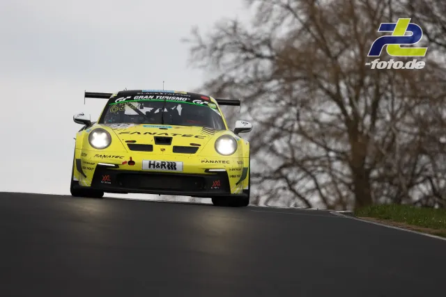 Gelber Porsche 911 GT3 R von Manthey Racing in der Kuppe auf der Nürburgring-Nordschleife bei bewölktem Wetter mit kahlen Bäumen im Hintergrund.