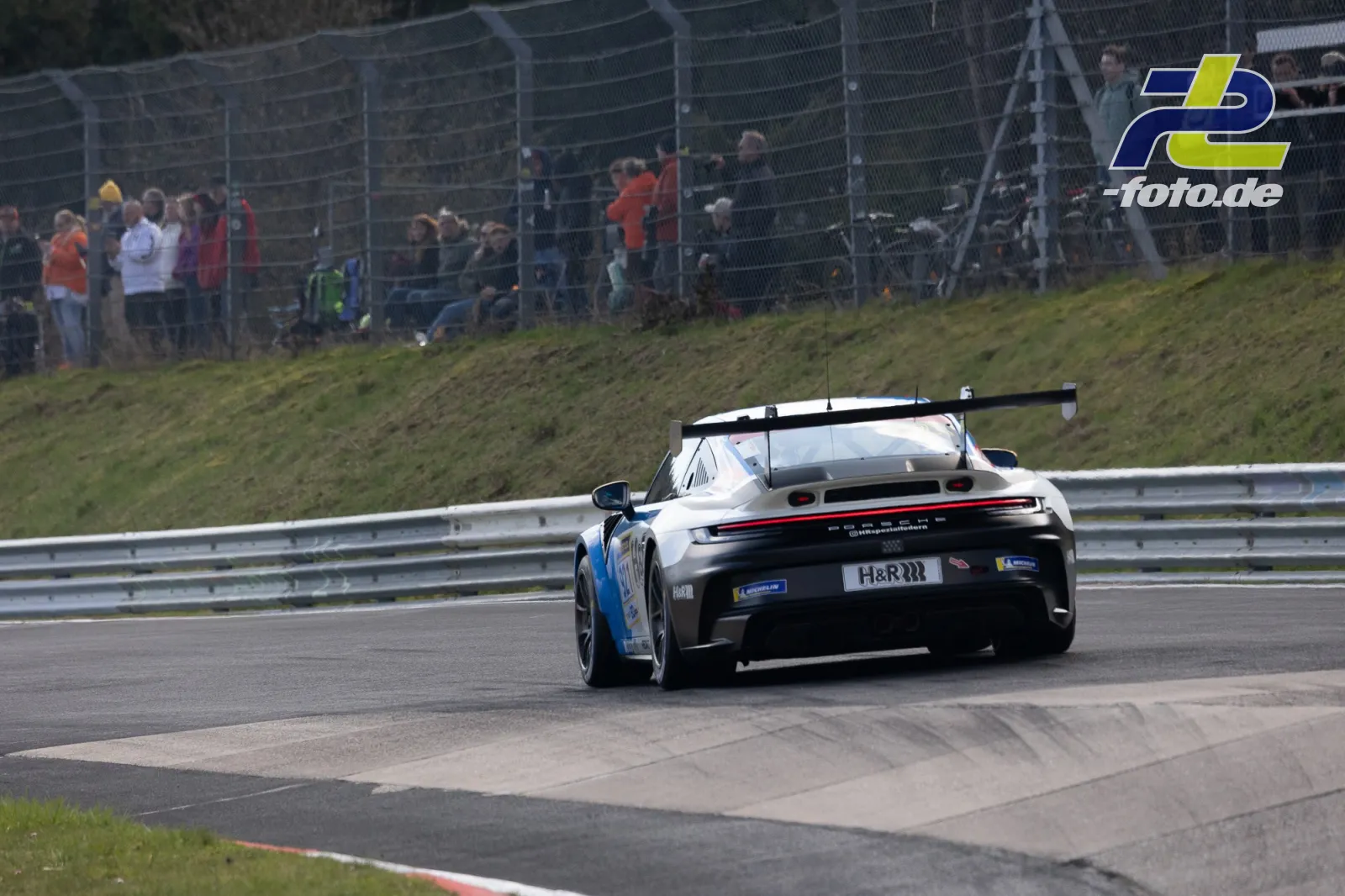 Porsche 911 GT3 Cup in weiß-blauer Lackierung auf der Nordschleife beim 58. ADAC Barbarossapreis, Zuschauer am Streckenrand