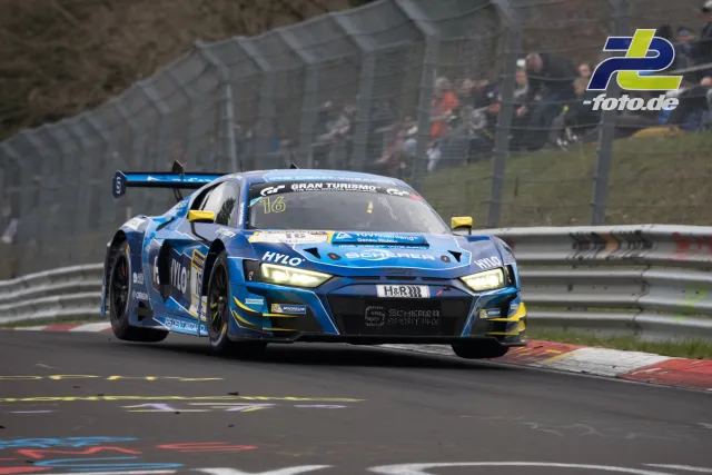 Blauer Audi R8 LMS GT3 Nr. 16 in Kurve auf der Nürburgring-Nordschleife, Zuschauer im Hintergrund. NLS Rennen.