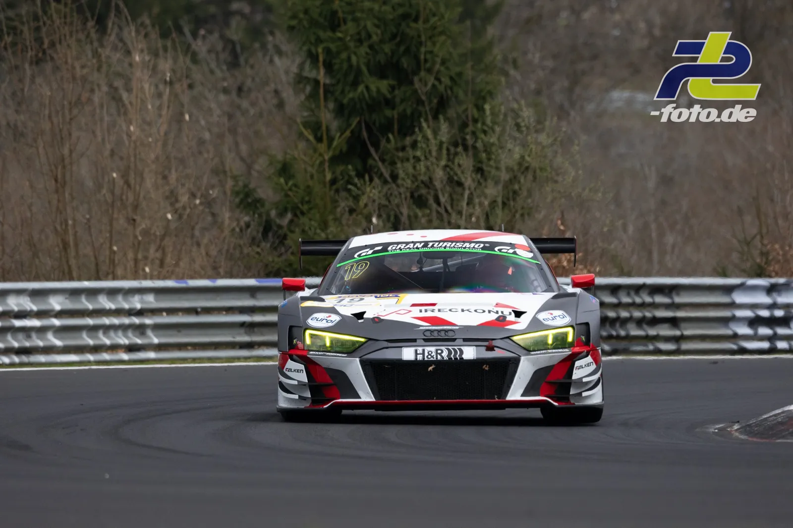 Audi R8 LMS GT3 mit Startnummer 19 in weiß-rot-schwarzer Lackierung frontal auf der Nordschleife während des NLS-Rennens.