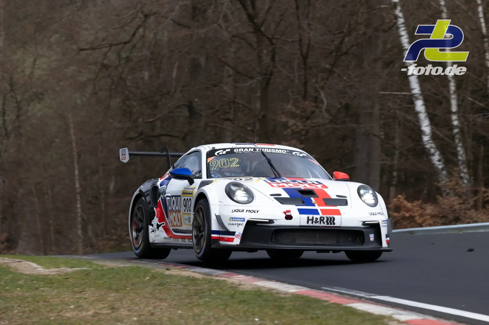 Porsche 911 GT3 R (902) in weiß mit blau-roten Streifen beim NLS-Rennen auf der Nordschleife.