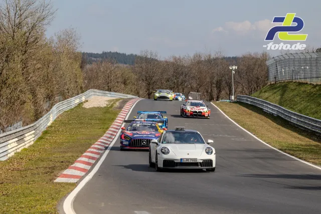 Weißer Porsche 911 mit Kennzeichen angeführt von GT3-Rennwagen auf der Nordschleife, Nürburgring.