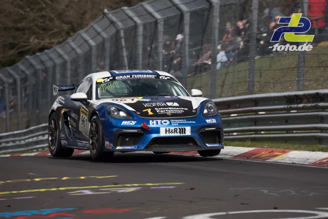 Porsche Cayman GT4 mit Startnummer 961 auf der Nordschleife während des ADAC Barbarossapreis, Zuschauer hinter Fangzaun.