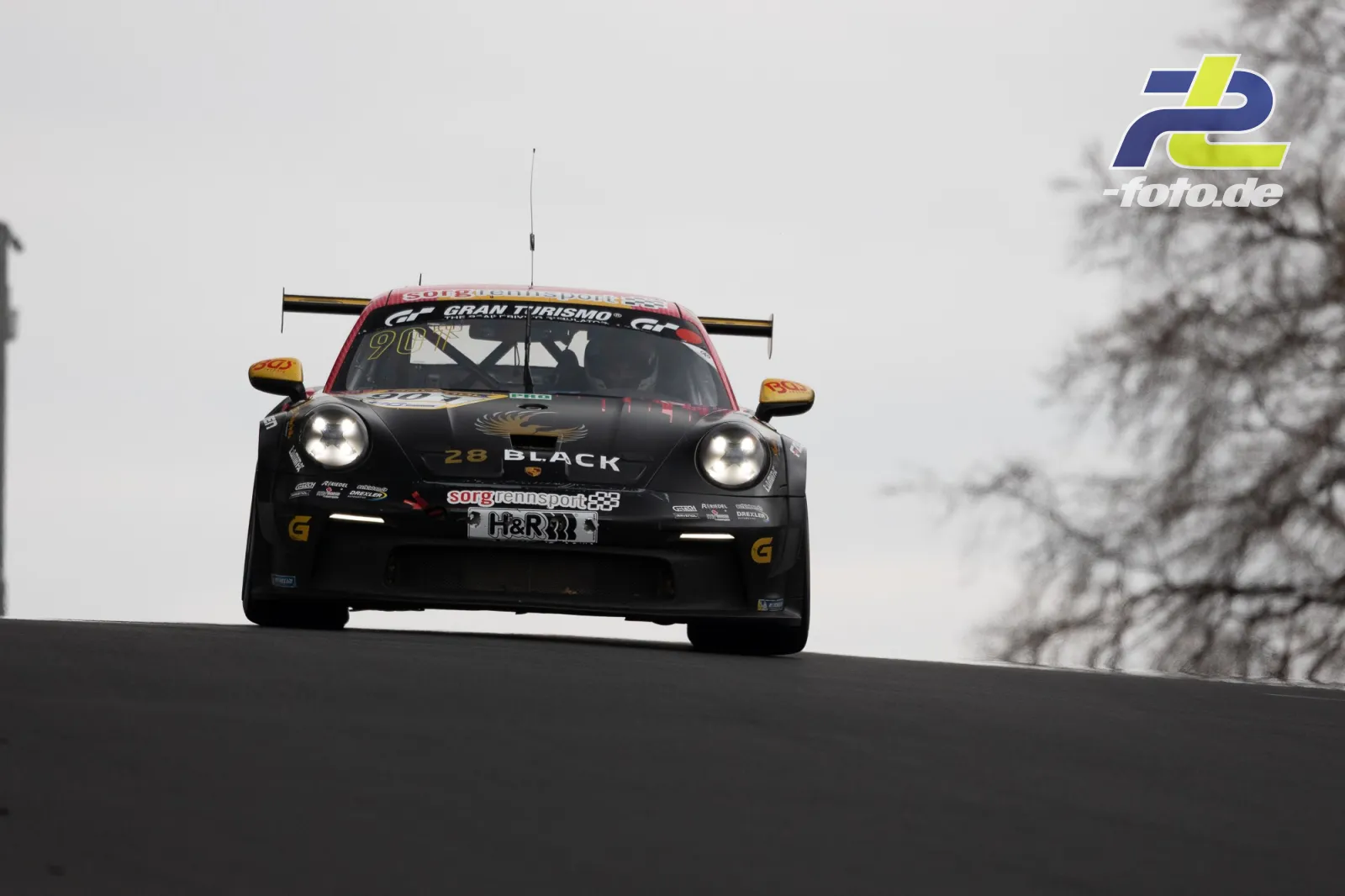 Porsche 911 GT3 Cup mit Startnummer 901 in Kuppe auf der Nürburgring-Nordschleife, schwarz-rote Lackierung, eingeschaltete Scheinwerfer