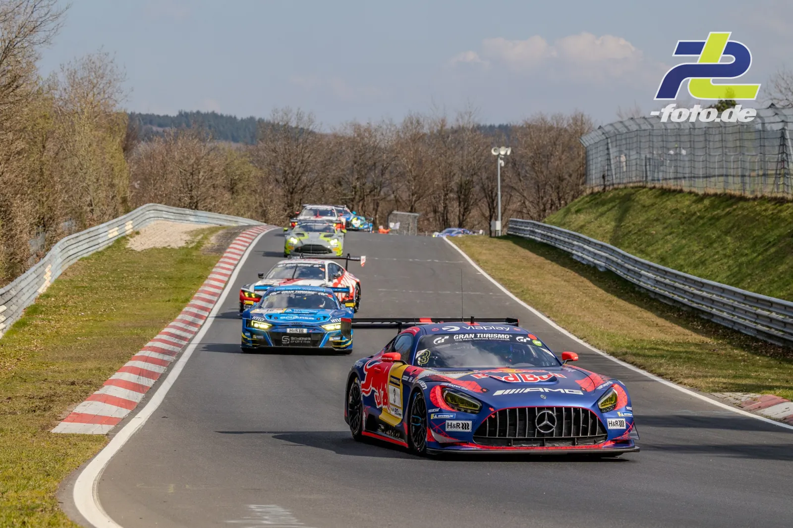 Rennfahrzeuge in Reihe auf der Nordschleife, angeführt von einem Mercedes-AMG GT3 in Red-Bull-Lackierung auf einer Geraden am Nürburgring.