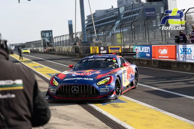 Mercedes-AMG GT3 #1 in Red Bull-Lackierung fährt aus der Boxengasse des Nürburgrings, weitere Fahrzeuge im Hintergrund.