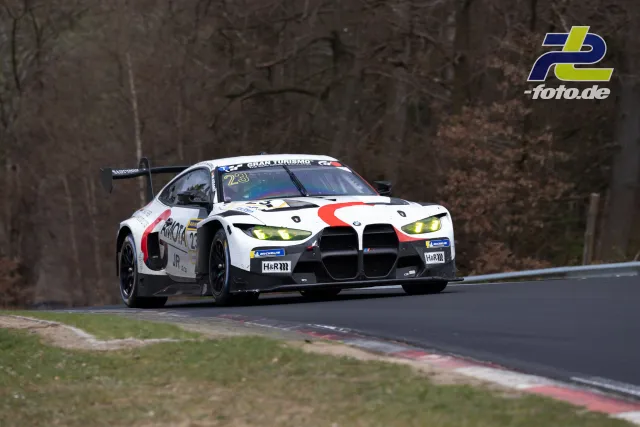 BMW M4 GT3 mit Startnummer 23 in Kurve auf der Nürburgring-Nordschleife beim NLS-Rennen, Waldkulisse im Hintergrund