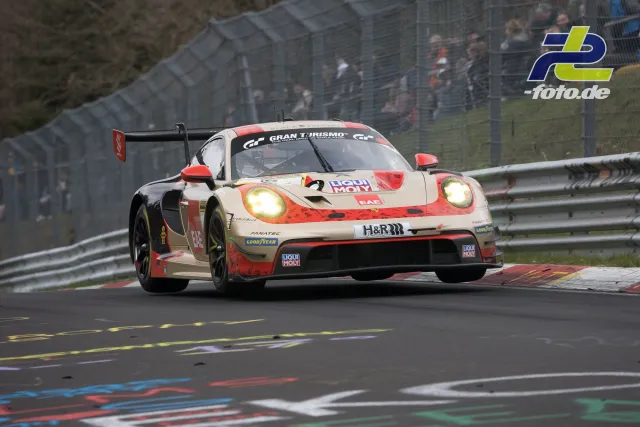 Porsche 911 GT3 R in weiß-rot während Rennen auf der Nürburgring-Nordschleife mit eingeschalteten Scheinwerfern