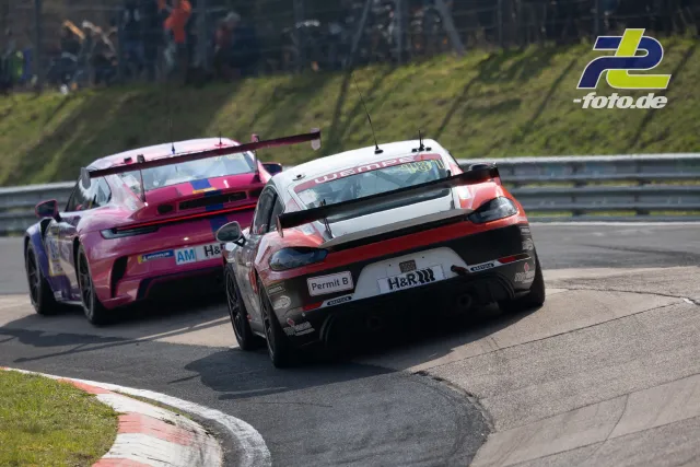Zwei Porsche im Zweikampf durch eine Kurve auf der Nordschleife des Nürburgrings beim NLS-Rennen.