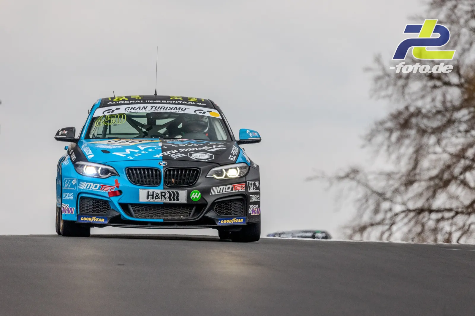 BMW Rennwagen in blau-schwarzer Lackierung auf der Kuppe der Nürburgring-Nordschleife, winterliche Atmosphäre mit Schnee am Streckenrand