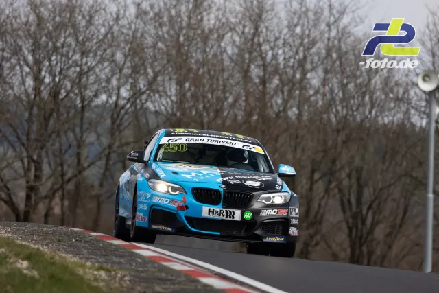 BMW im VLN-Rennen auf der Nordschleife, Sprung über eine Kuppe vor Baumkulisse bei bewölktem Wetter