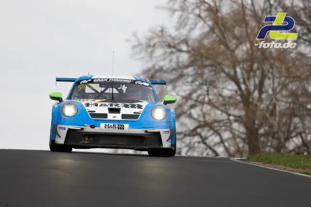 Porsche 911 GT3 R in blau-weiß mit H&R-Schriftzug springt über die Kuppe auf der Nordschleife des Nürburgrings.