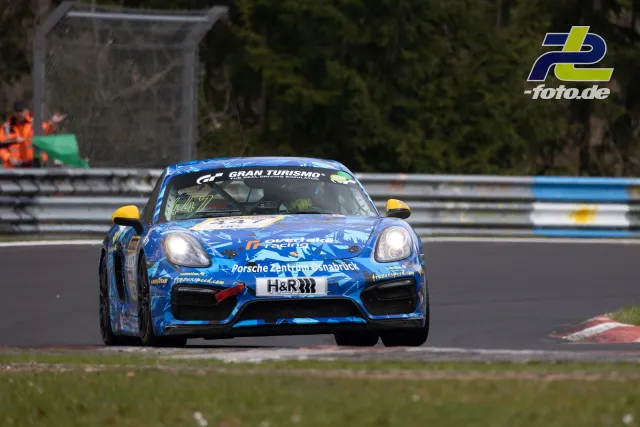 Porsche Cayman GT4 in blauer Lackierung mit gelben Spiegeln auf der Nordschleife während des NLS-Rennens