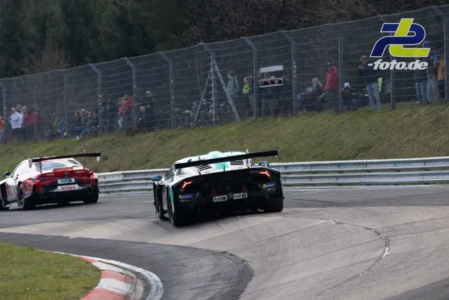 Zwei GT-Sportwagen in Kurve auf der Nordschleife, Zuschauer am Streckenzaun, NLS-Rennen