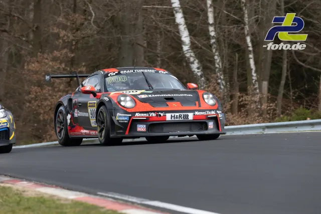 Porsche 911 GT3 Cup mit Startnummer 900 in schwarz-oranger Lackierung im Rennen auf der Nordschleife, Birken im Hintergrund