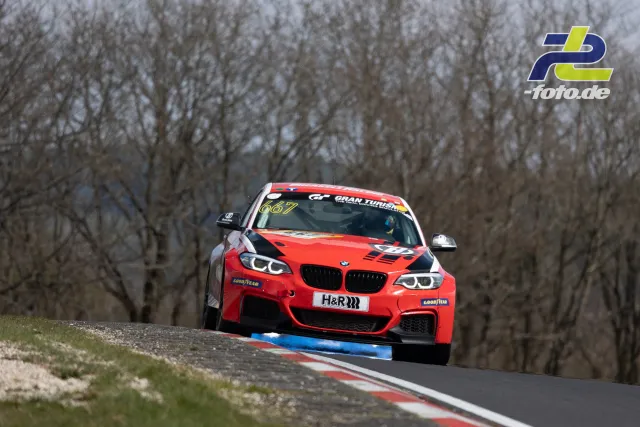 Roter BMW M240i Cup auf der Nordschleife beim NLS-Rennen, Kurve über blau-rote Randsteine, Wald im Hintergrund
